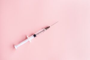 close up of a syringe placed on a pink background
