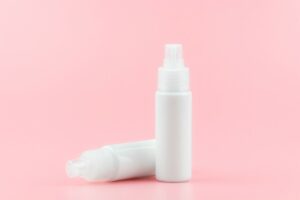 close up of a white medicine spray bottle placed on a pink background