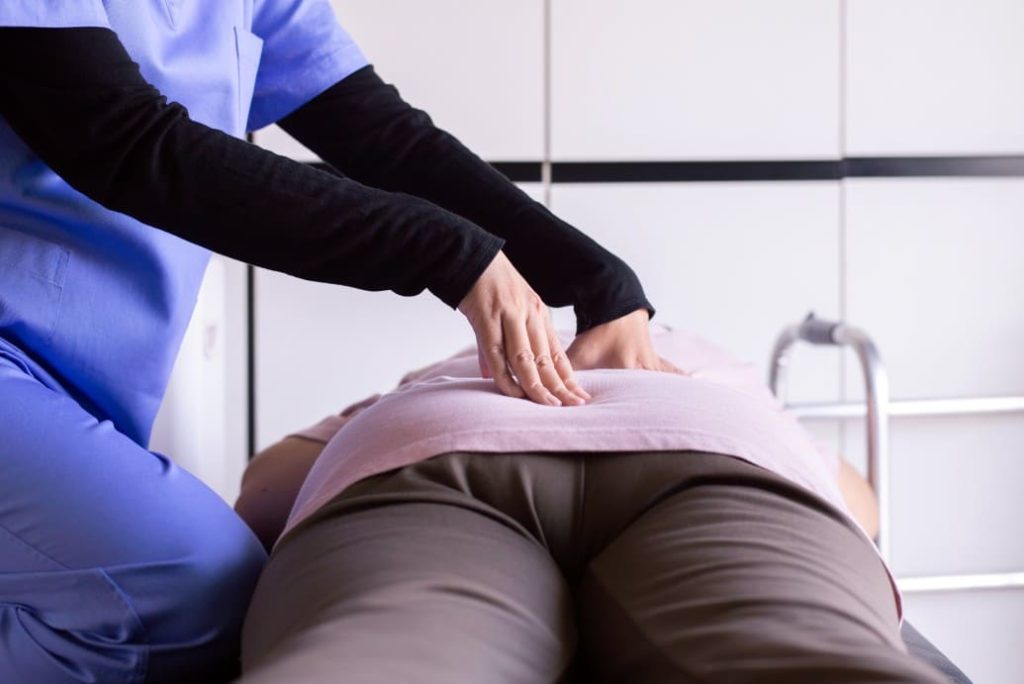 physician finding the sore spot on patients back by pressing with her hands