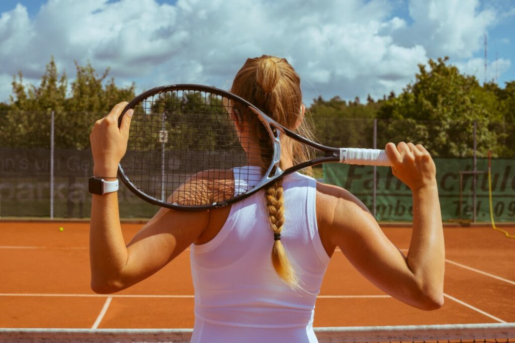 A woman holding a tennis racket behind her head